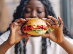 woman holding cheeseburger at restaurant