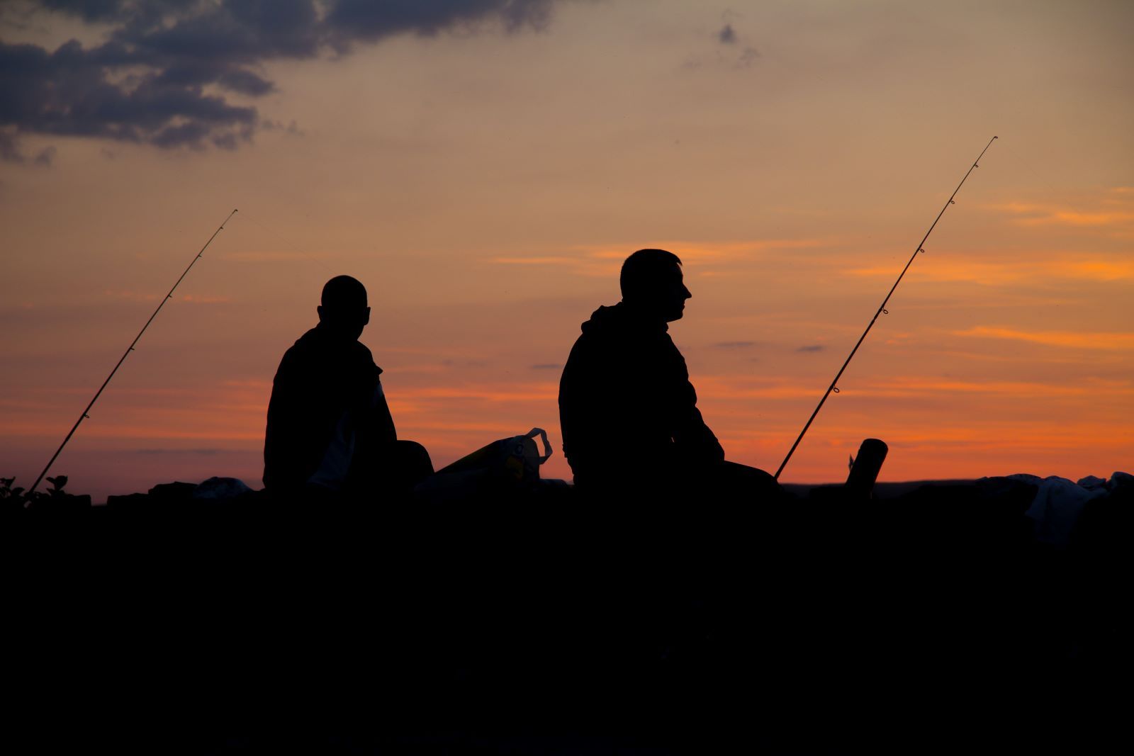 two men fishing at sunset